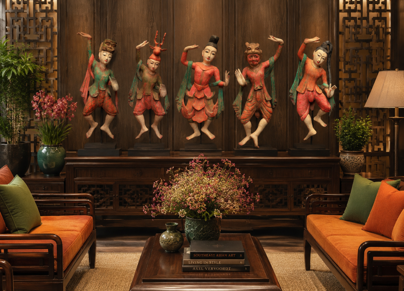 Five carved Burmese Nat wall figures displayed in a traditional teak wood lounge